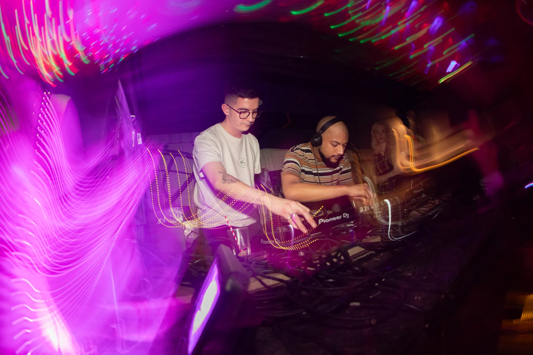 DJ behind the decks with magenta light streaks across The Bunker